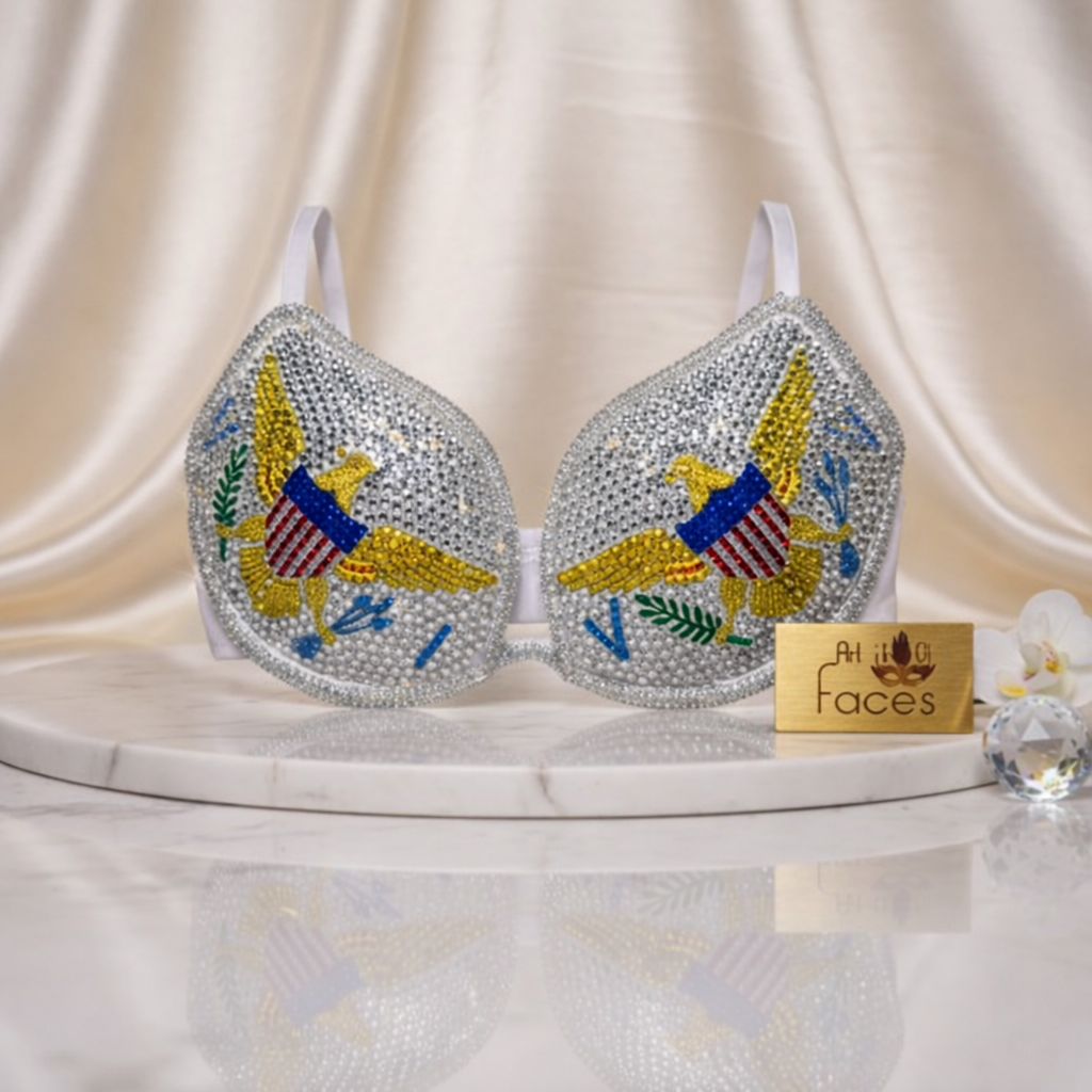 Decorative bra with colorful eagle design on a white surface with 'At Your Faces' sign.