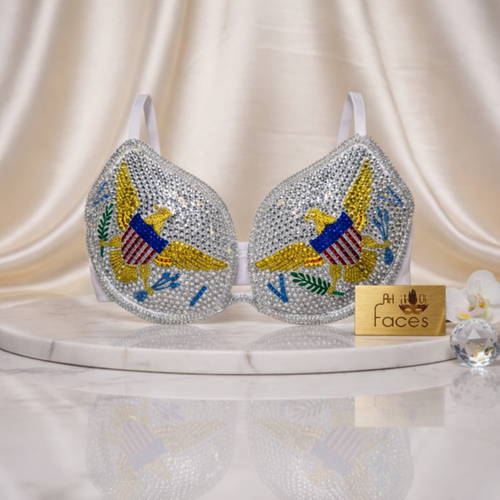 Decorative bra with colorful eagle design on a white surface with 'At Your Faces' sign.